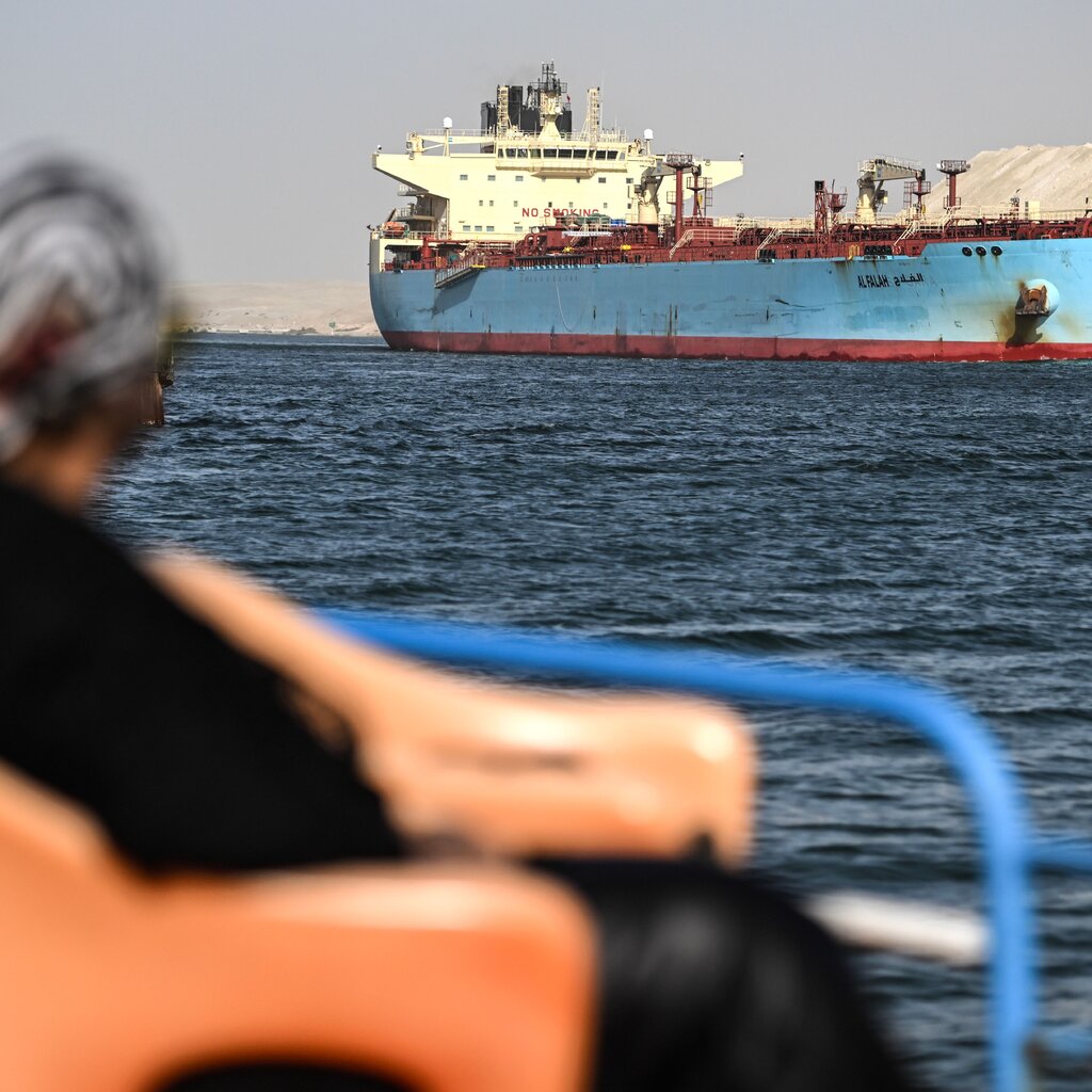 A person watches as a ship crosses the Suez Canal.