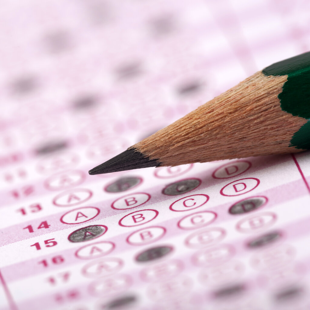 A pencil laying on top of a lettered multiple-choice test sheet with bubbles shaded in.