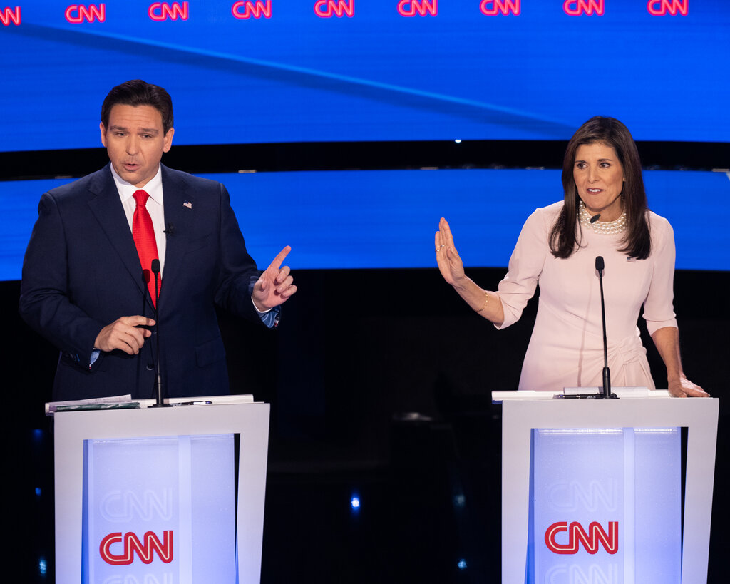 Ron DeSantis, left, and Nikki Haley, standing behind lecterns that say CNN. He is extending his left index finger and she is holding her right hand out to the side, as if telling him to stop. 