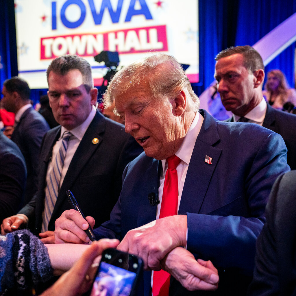 Donald Trump signs a person’s arm after a Fox News town hall event, as security officers stand alongside him. 