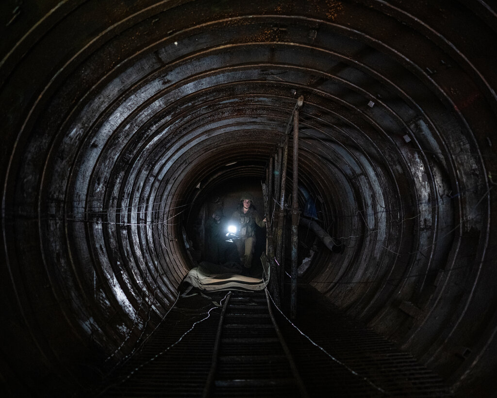 The interior of a large tunnel. A soldier is in the background holding a light.