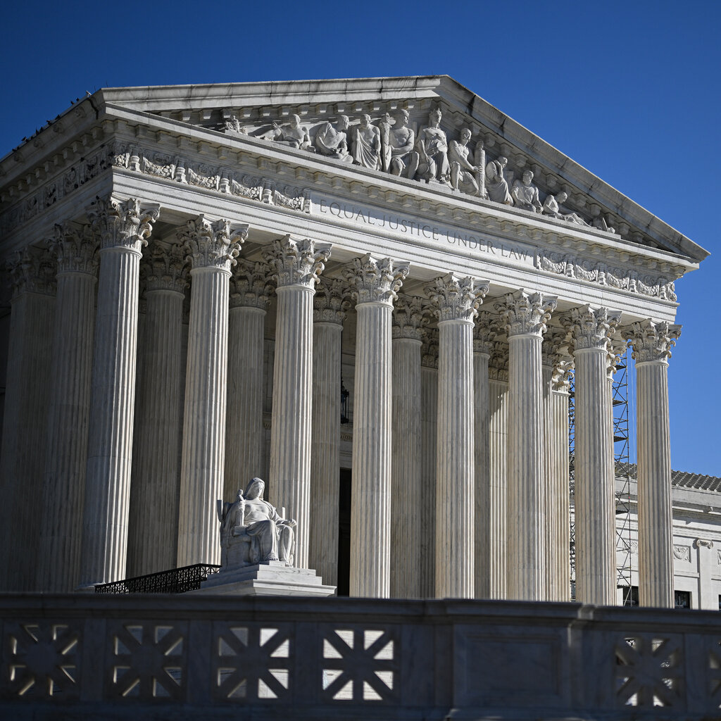The exterior of the U.S. Supreme Court building against a blue, cloudless sky.