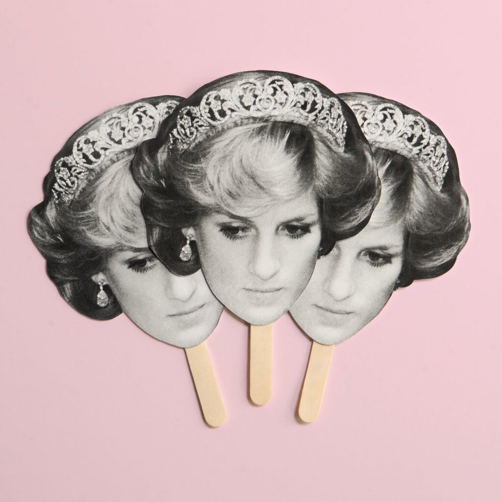 A photo illustration shows three hand fans, with popsicle stick handles and the same black-and-white image of Princess Diana, who is wearing a tiara. The background of the illustration is pink.