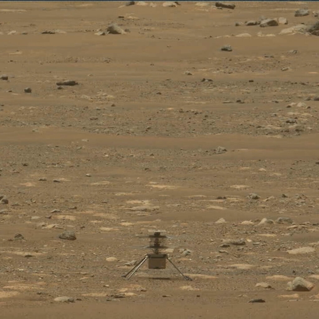 A tiny robotic helicopter with two sets of blades sits on the Martian surface.