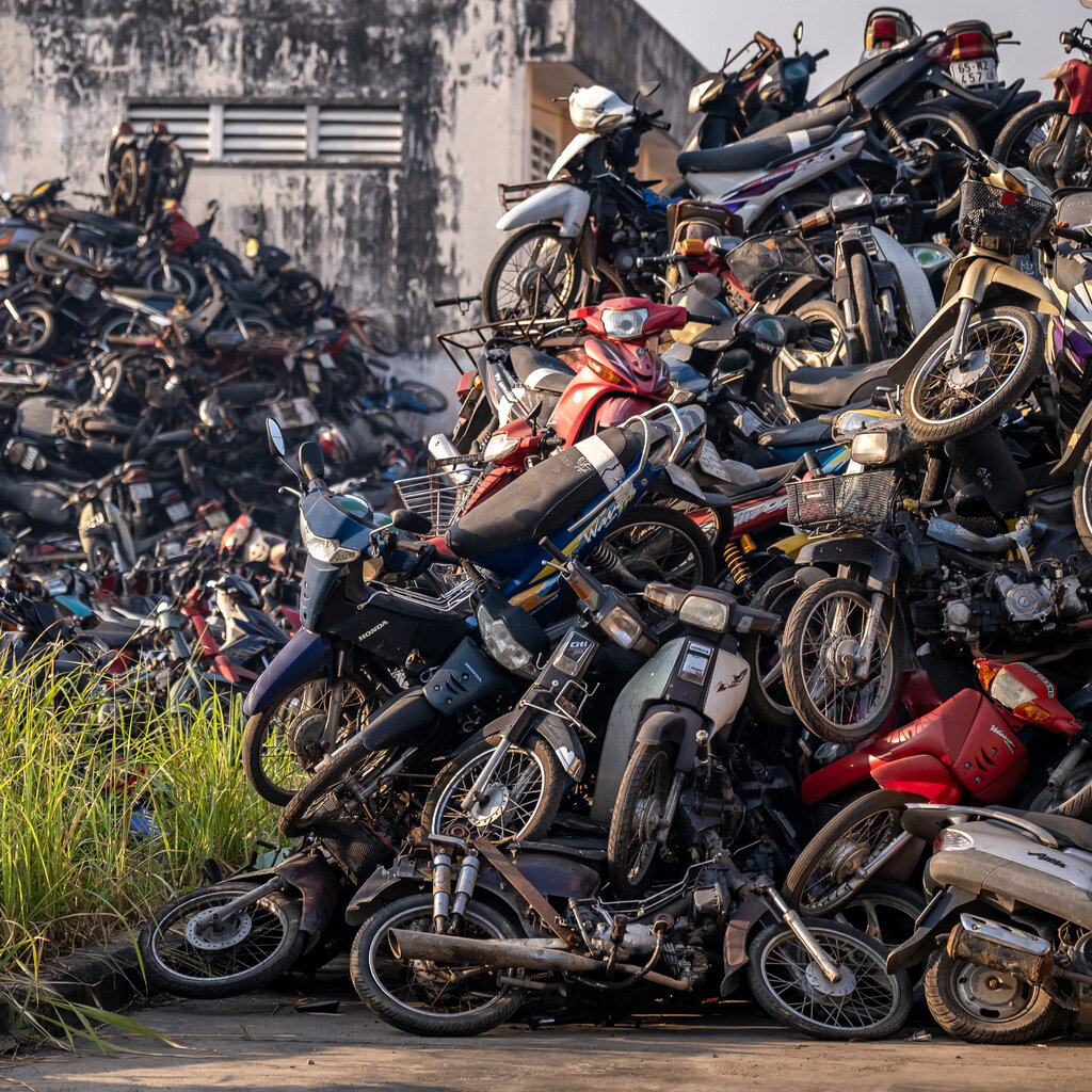 Motorbikes piled on top of each other in two heaps.