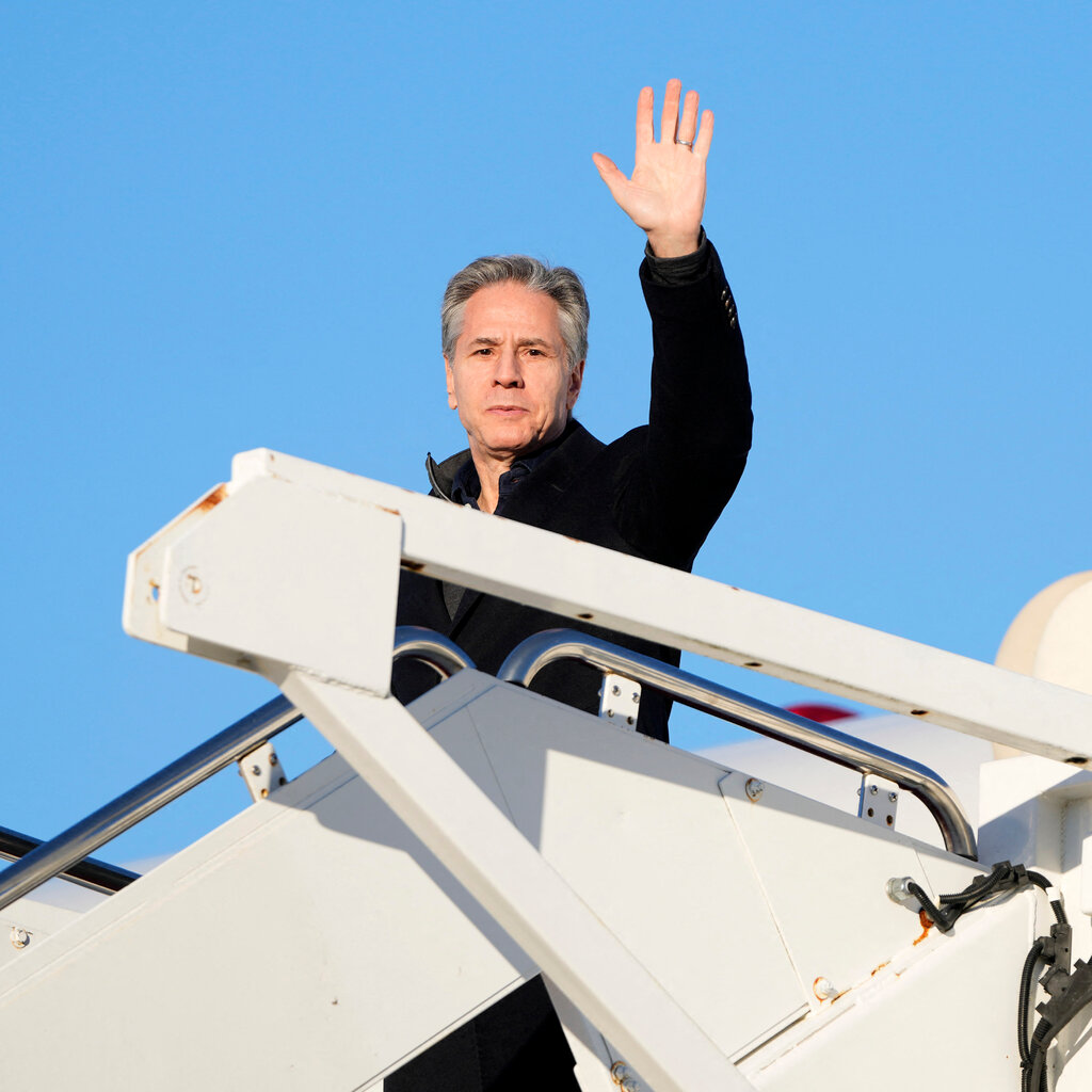 Secretary of State Antony Blinken waves as he boards a plane.