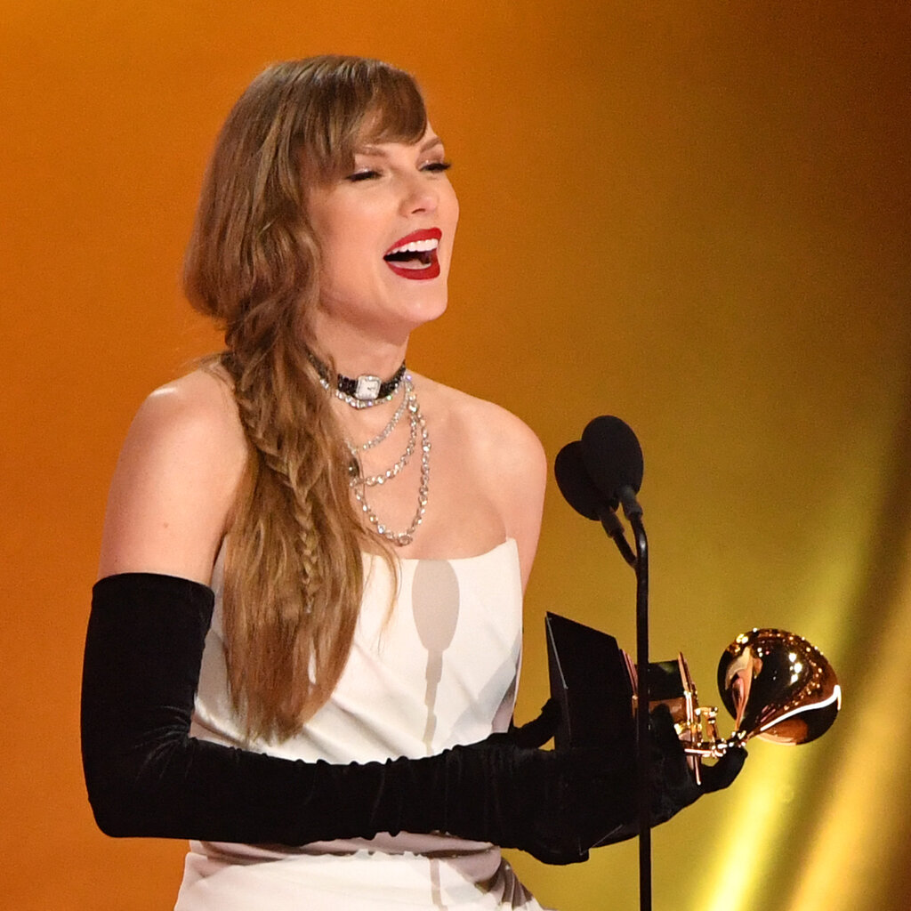 Taylor Swift holding a Grammy onstage. 