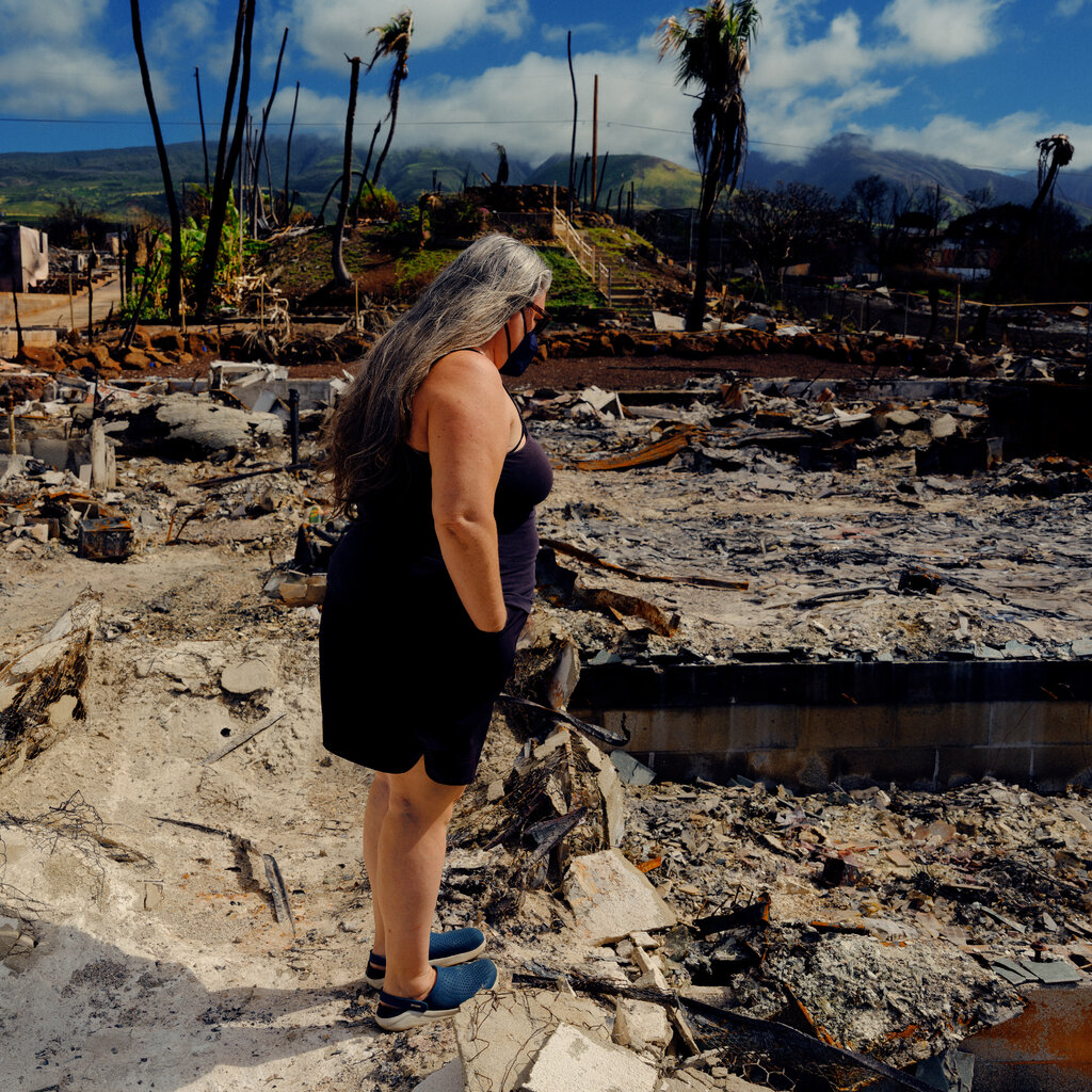 A woman stands among debris. 