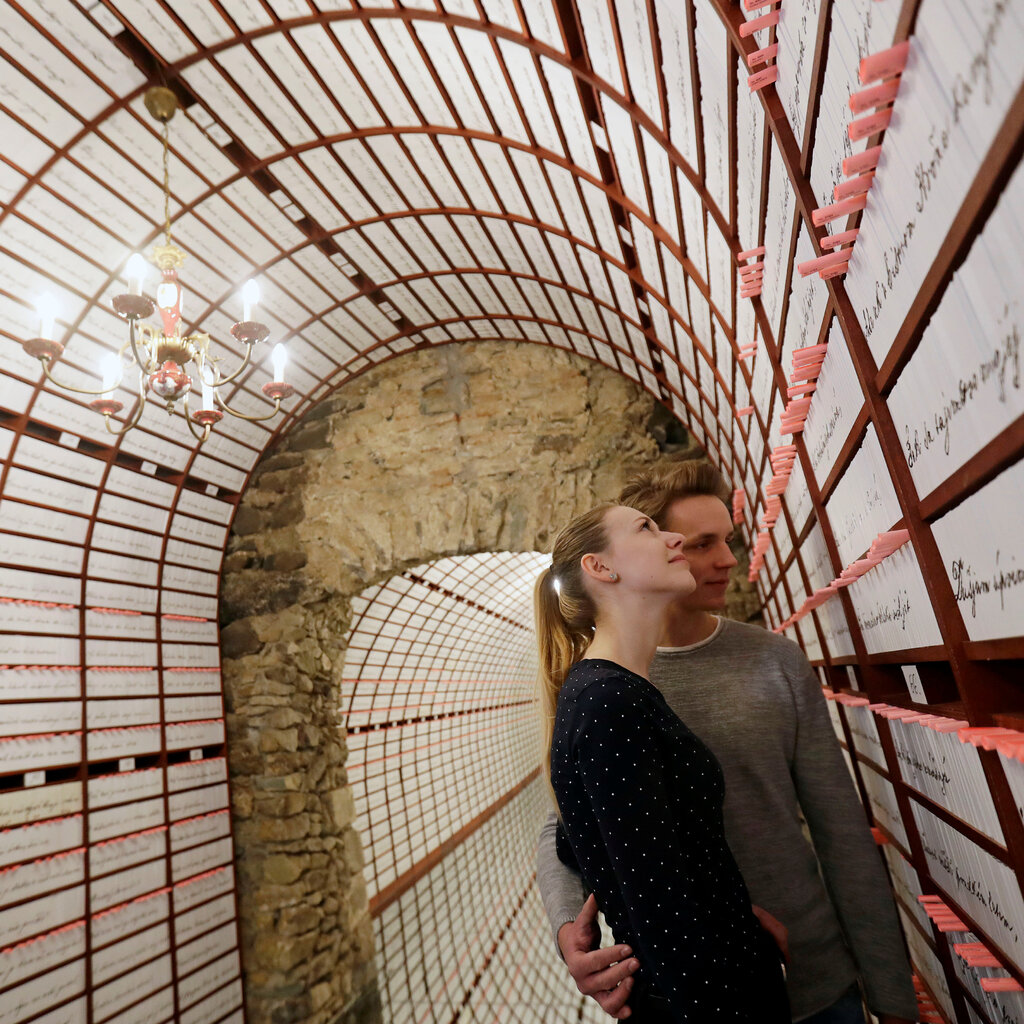A man and a woman stare at writing on the wall of an underground vault.