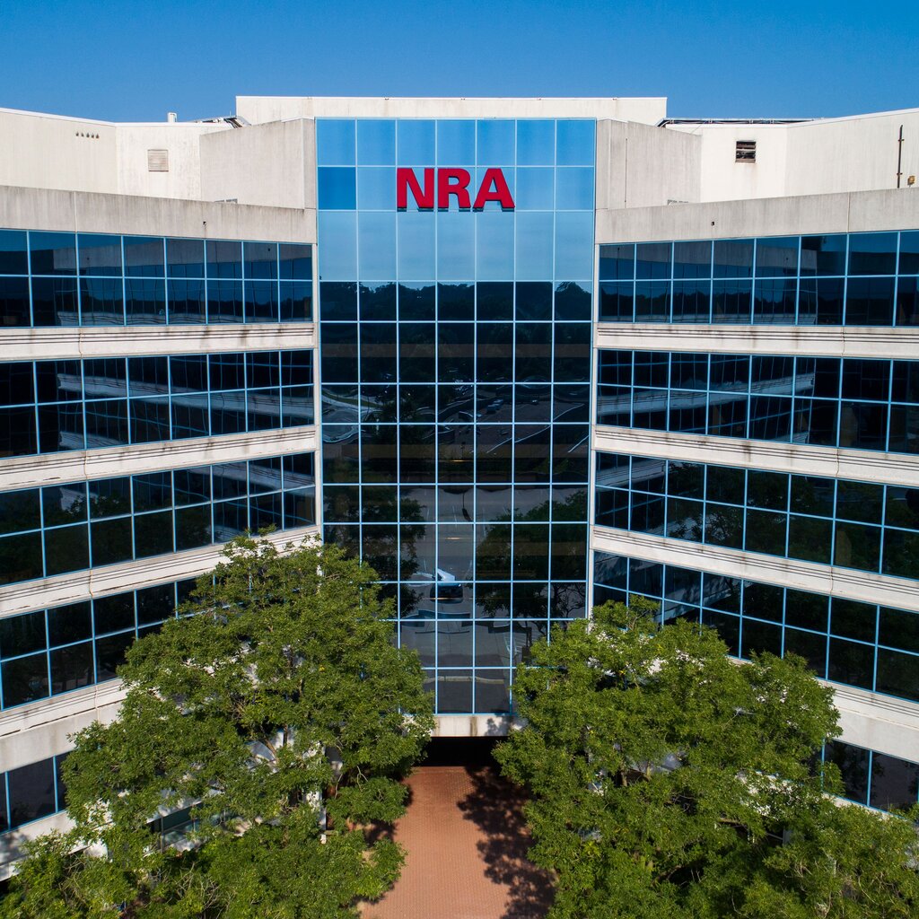 The exterior of a large, glass-fronted building with the red letters "NRA" in the center of windows near the top.