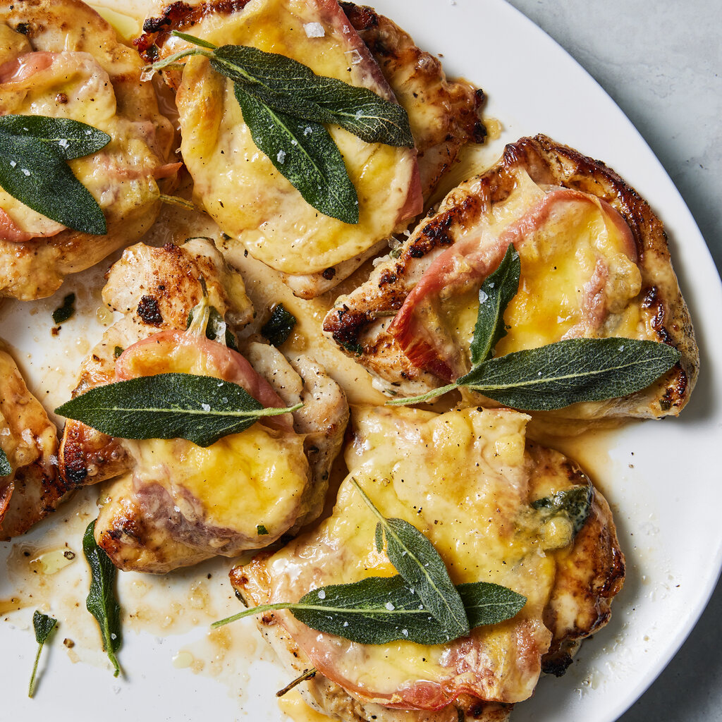 A white platter holds six chicken cutlets topped with prosciutto, melted cheese and sage leaves.