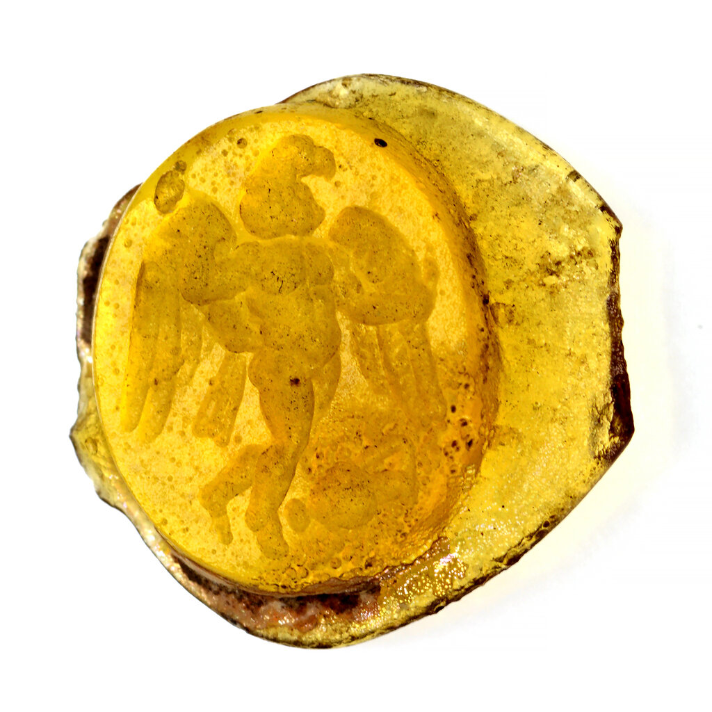 A photo of a yellow glass item, carved with a picture of a winged figure.