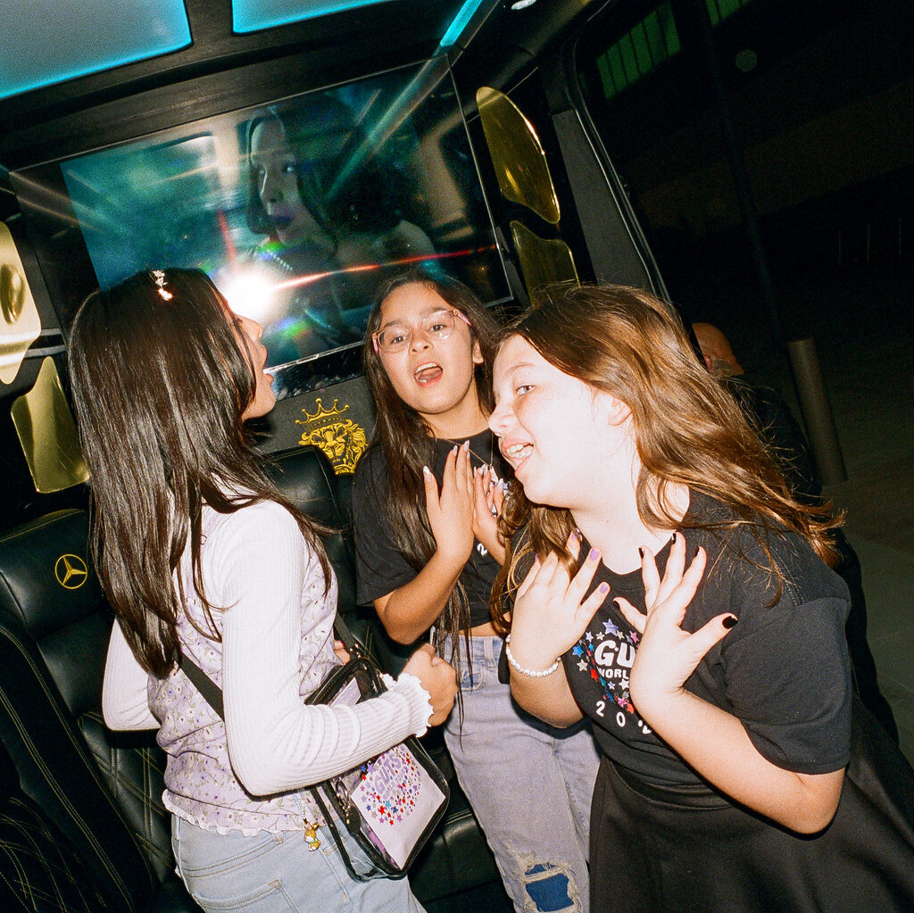 Three young Olivia Rodrigo fans are dancing and singing along to an Olivia Rodrigo music video in party bus. They are wearing "Guts" tour themed clothing.