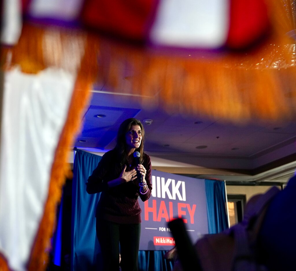 Nikki Haley standing onstage with her hand on her chest, speaking into a microphone.