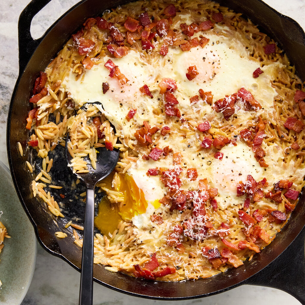 Orzo with eggs and pancetta in a skillet from above.