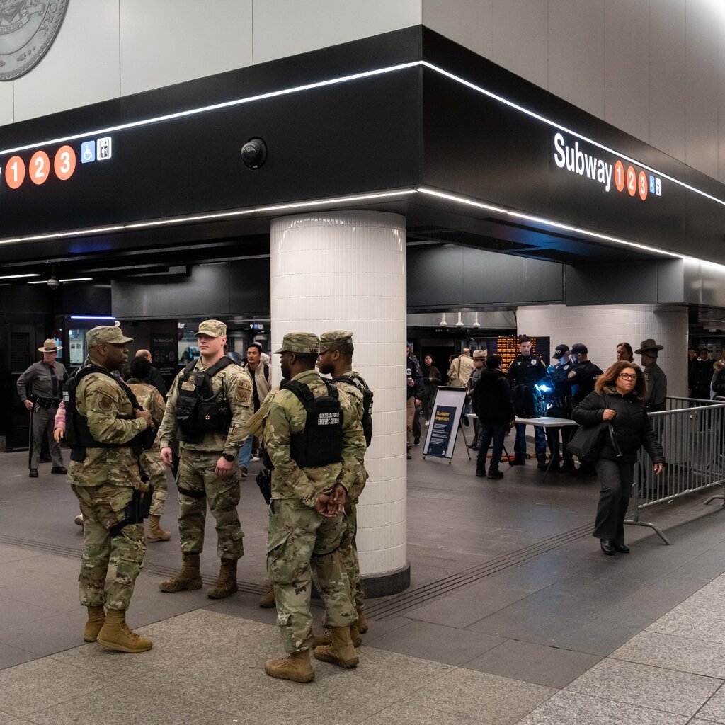 Members of the National Guard stand watch on Thursday as New York City police officers checked bags in the subway.