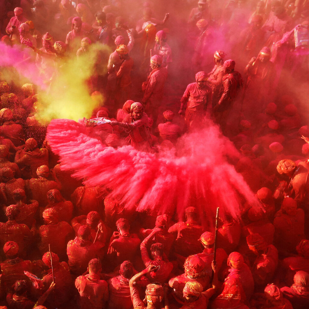 A crowd of celebrants are covered in red and pink powder.