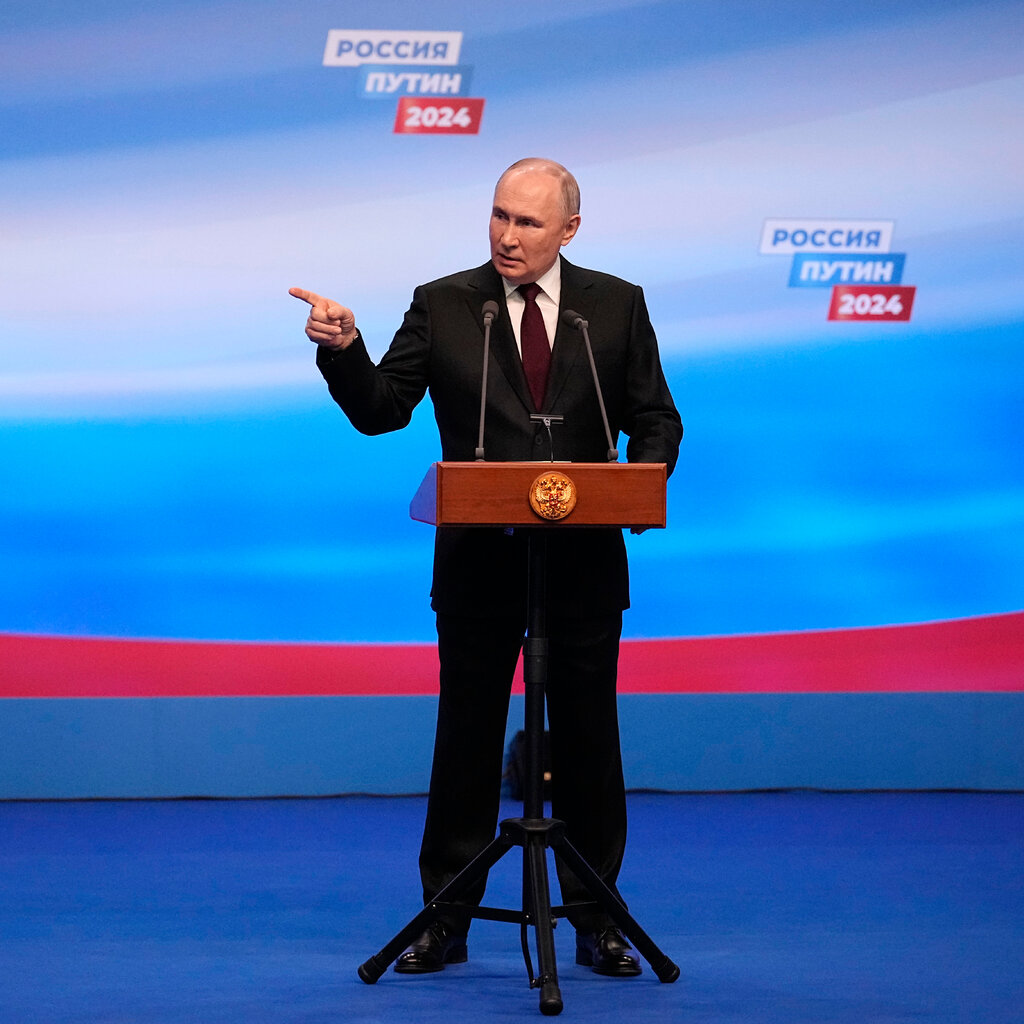 Vladimir Putin gives a speech from a lectern. 