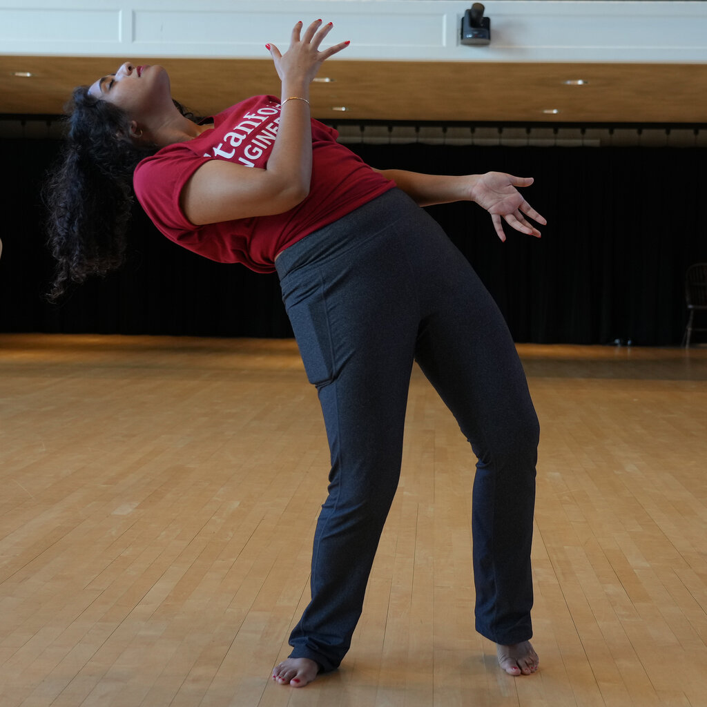 Kristi Maisha leans back with her hands in motion in her dance class.