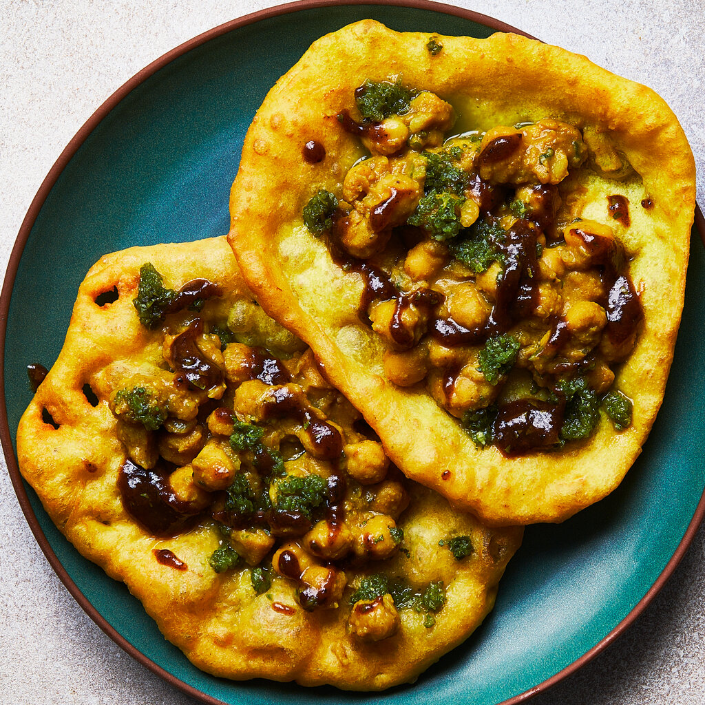 Two pieces of fried bread with chickpeas and chutney on a plate.