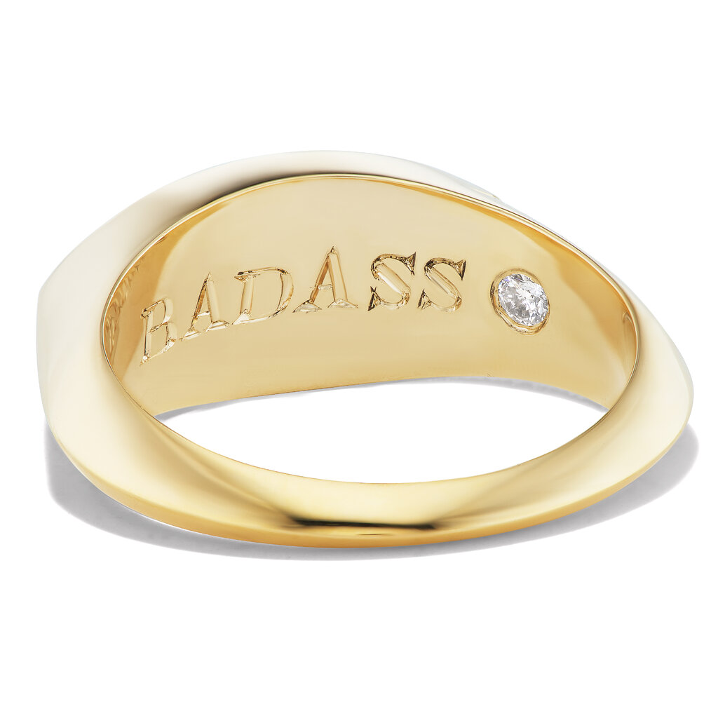 The interior of a gold band featuring a small diamond next to the word "badass."