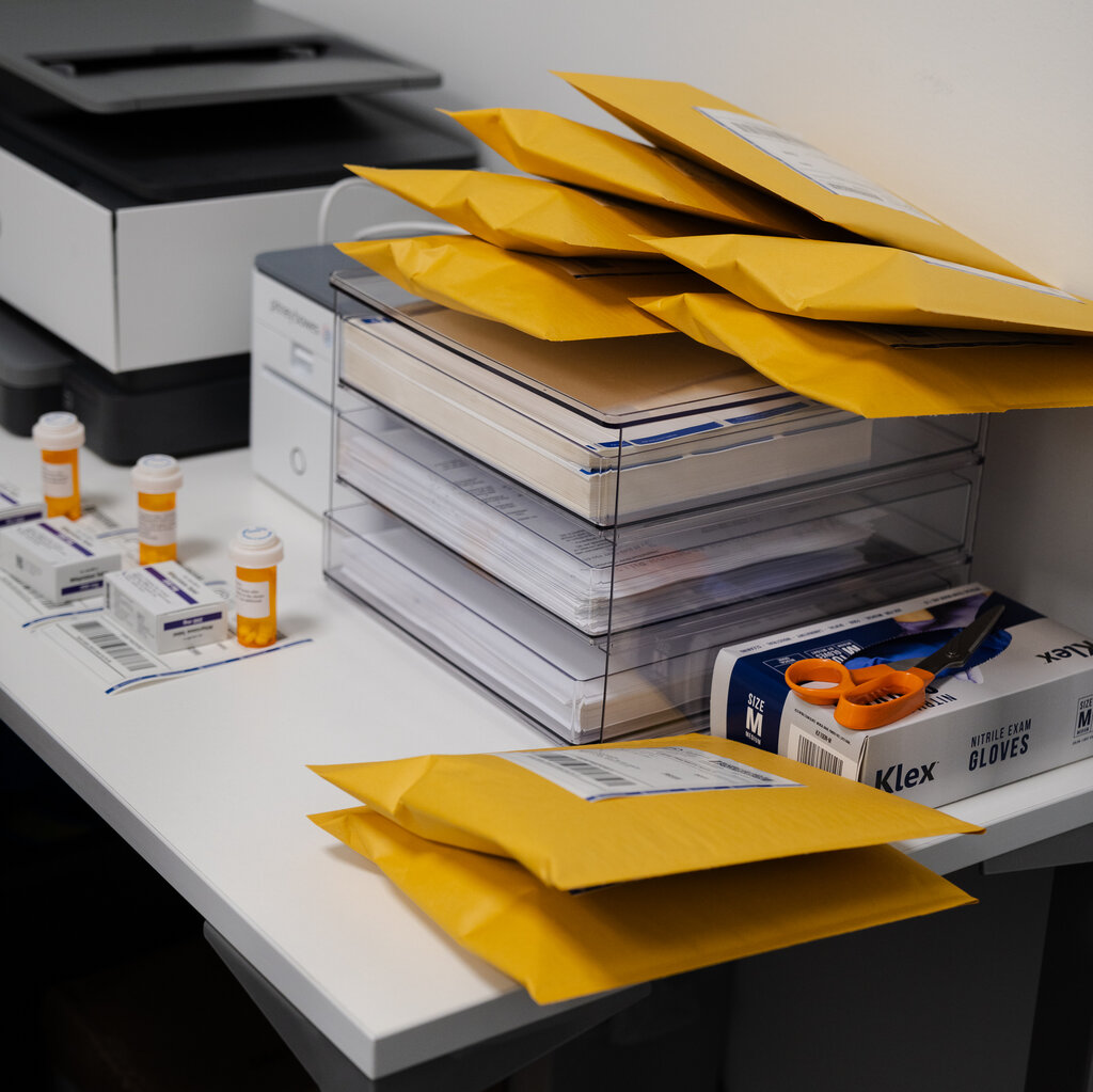 Bottles of pills and manila envelopes on a desk. 