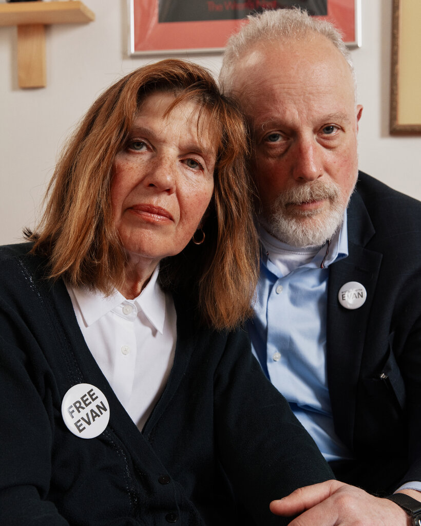 Ella Milman and Mikhail Gershkovich lean into each other for a portrait. She is wearing a button that says, “Free Evan.” His says, “I Stand With Evan.”