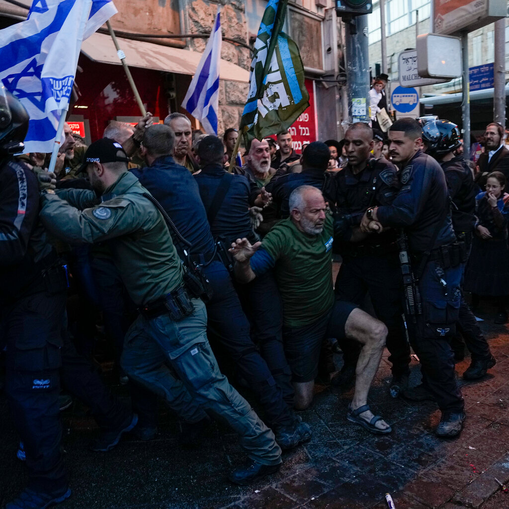 Demonstrators being pushed by police officers.