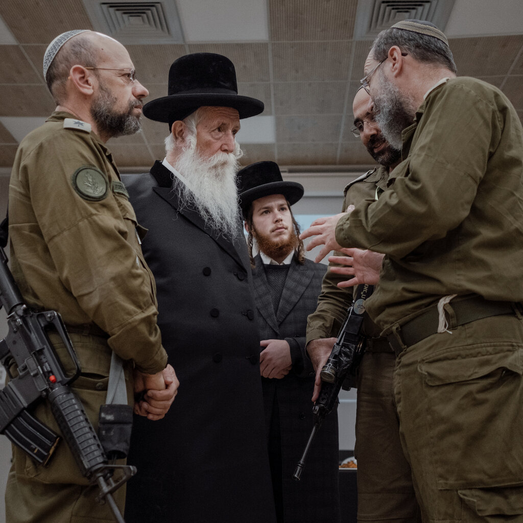Orthodox Jewish men speak with military officers. 