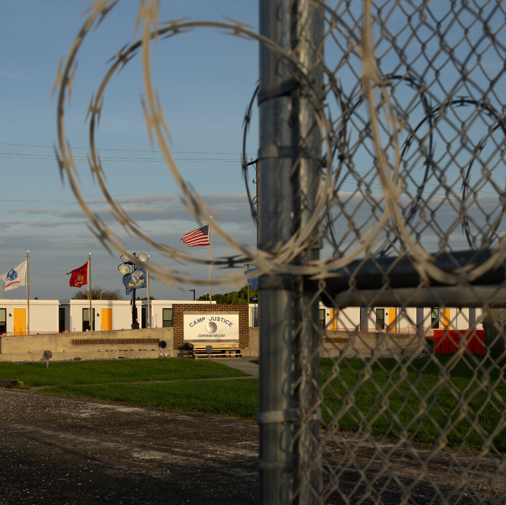 A chain-link fence in front of a sign saying "Camp Justice."
