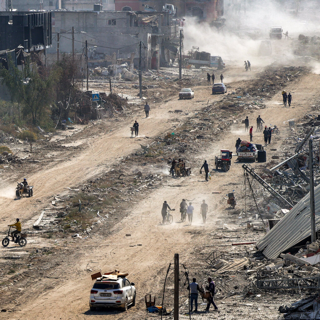 People and cars on a bombed-out road in Gaza. 