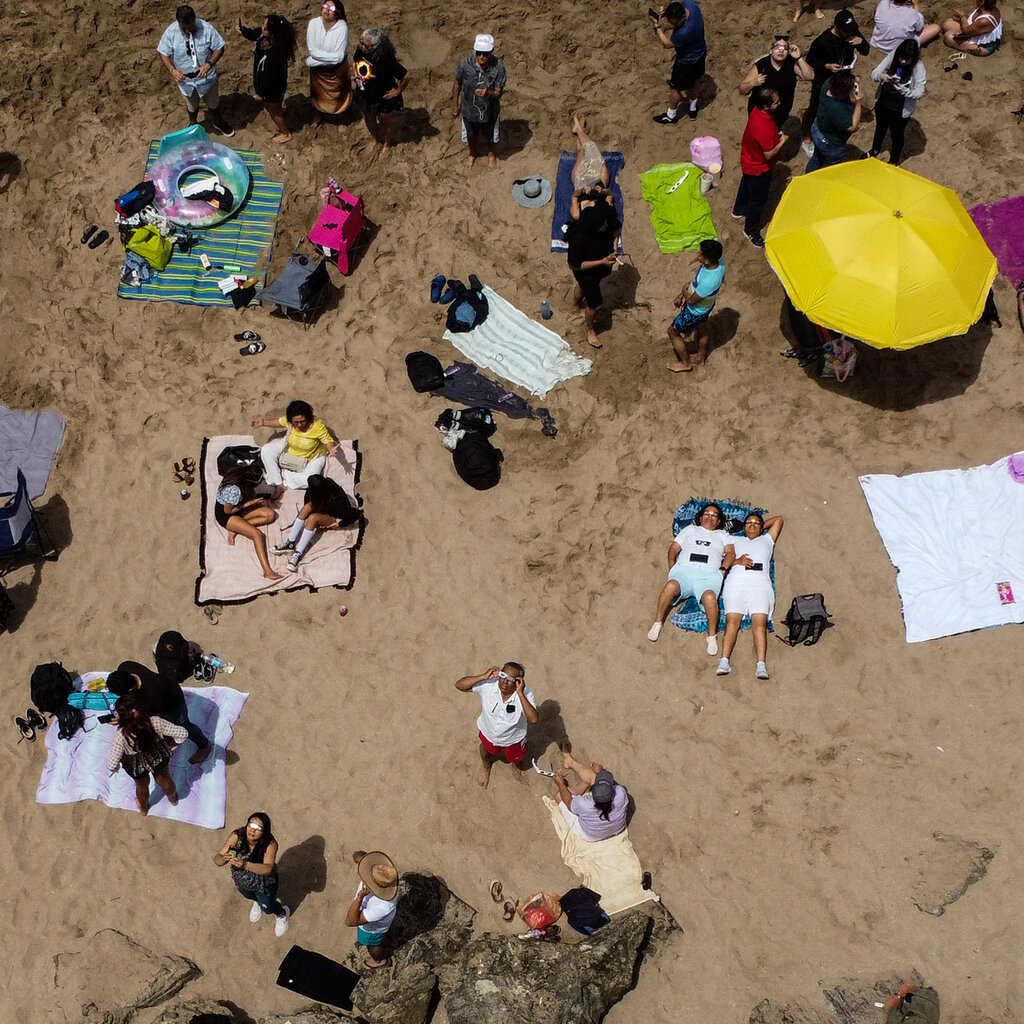 An aerial image of eclipse watchers on a beach. 