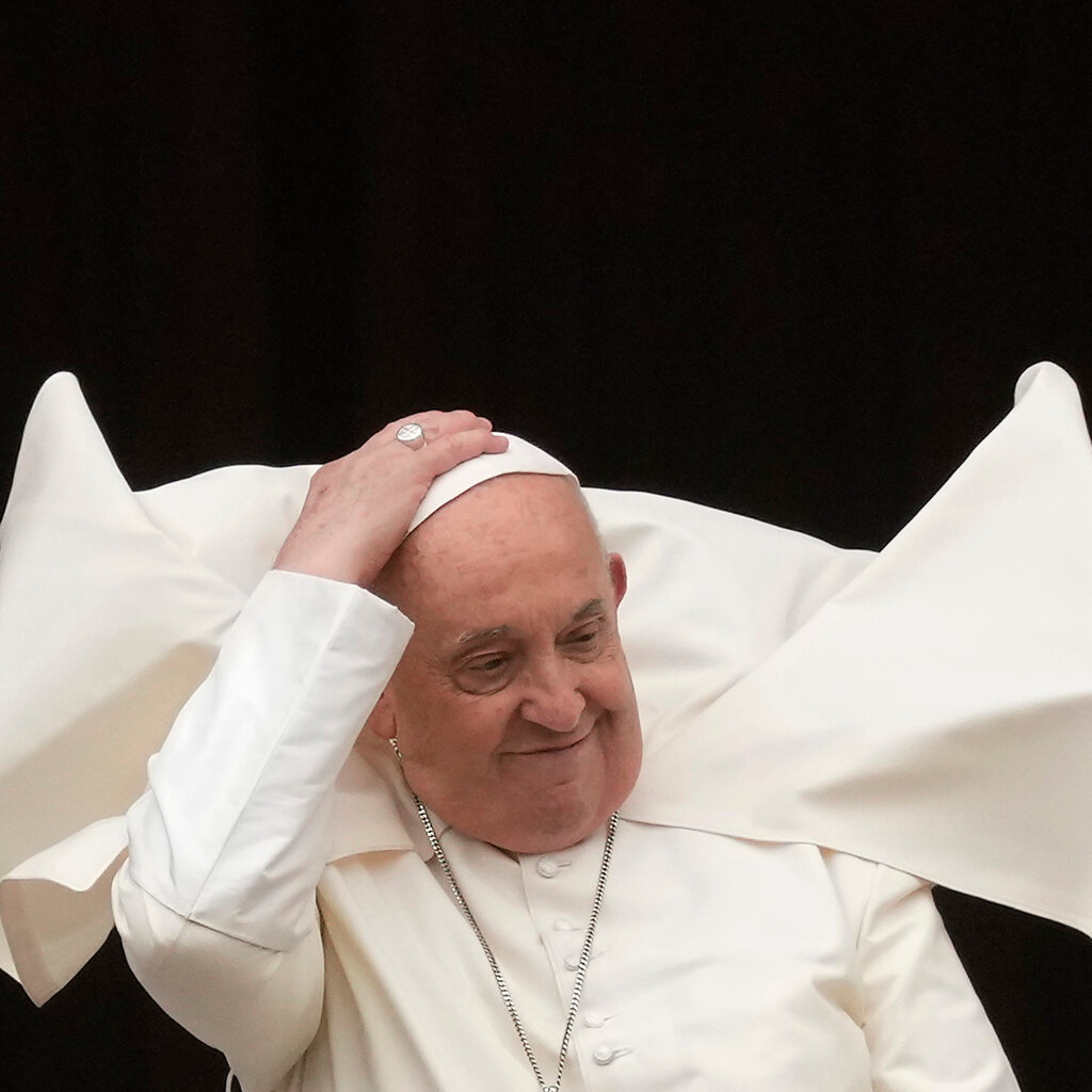 Pope Francis, white cape blowing in the wind.