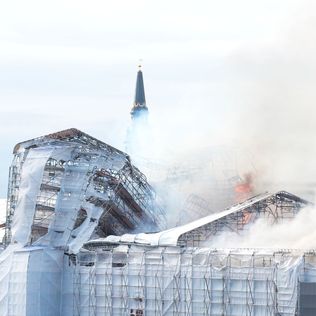 Smoke rises from a building encased in scaffolding. 