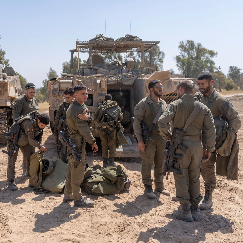Israeli soldiers stand next to personnel carriers. 
