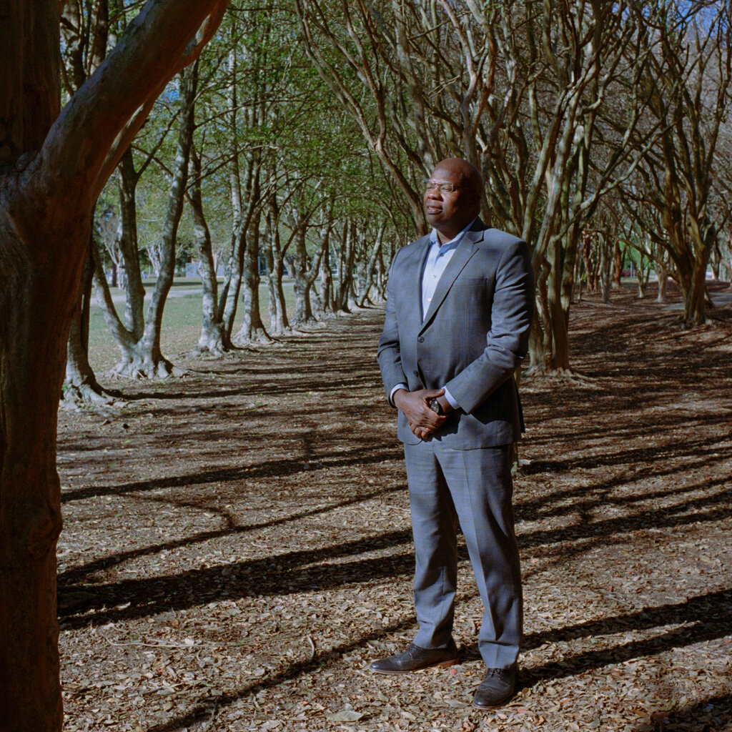 A man in a gray suit in a community park. 