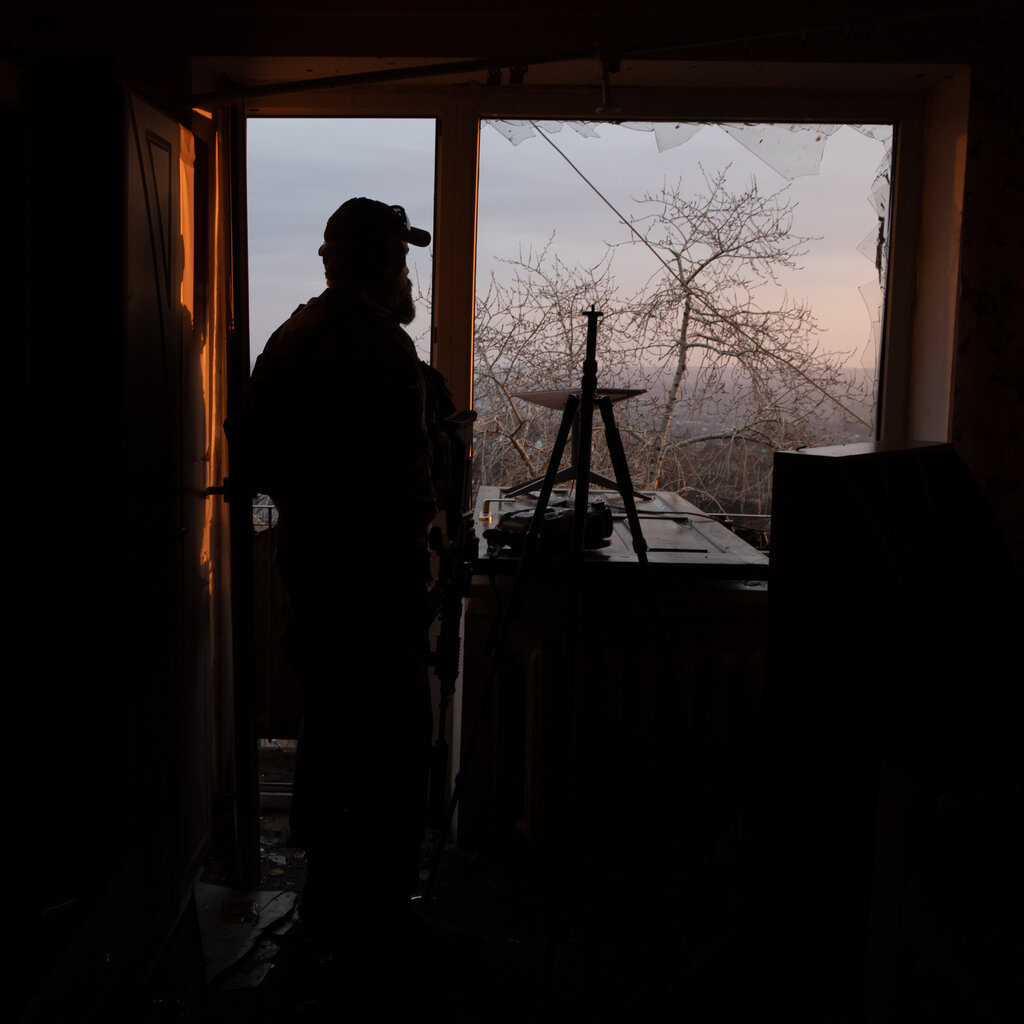 A silhouette of a soldier looking out a window with a Starlink satellite to the right of the frame.