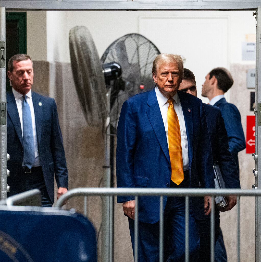 An image of Trump in a navy blue suit and orange tie outside the courtroom. 
