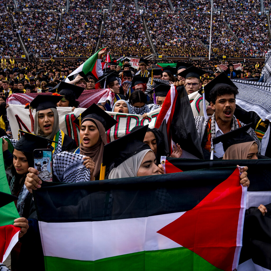 Protesters holding Palestinian flags in an arena. 
