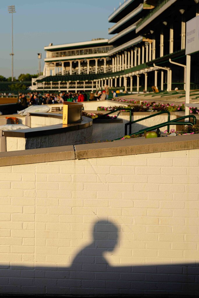 The shadow of a worker at Churchill Downs. Attendees are out of focus in the background. 