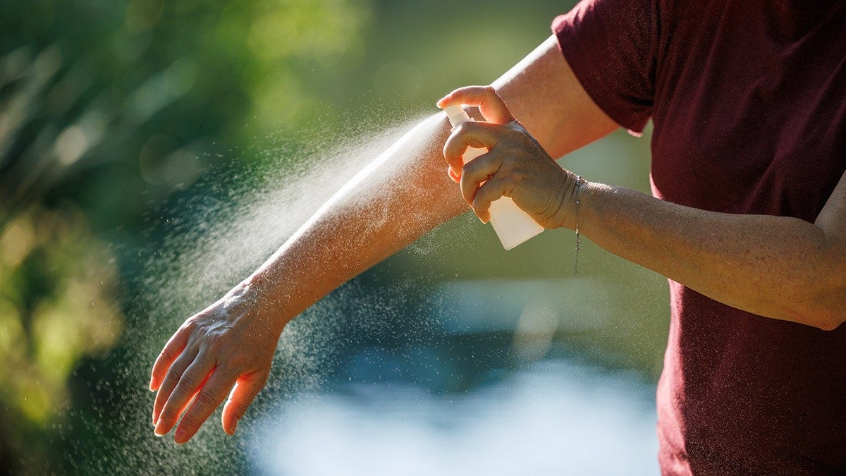 a person applies insect repellent to their arm a person applies insect repellent to their arm