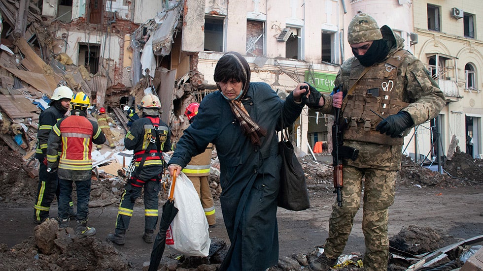 A volunteer of the Ukrainian Territorial Defense Forces assists a woman to cross the street in Kharkiv, Ukraine