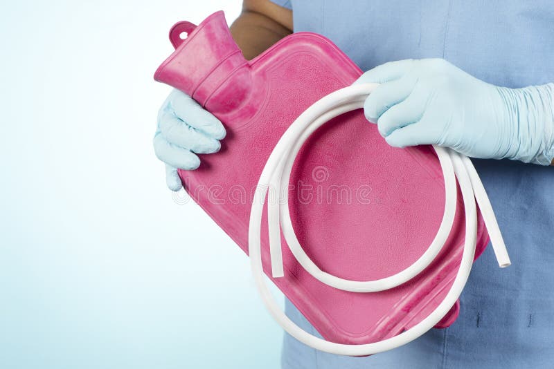 Enema Bag. Nurse holds enema bag with white tubing on blue stock images
