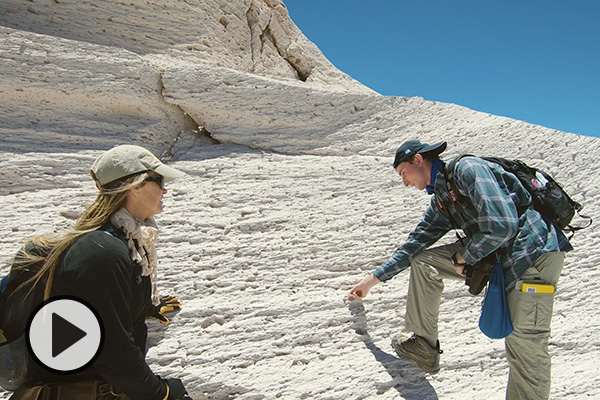 A professor and student explore a rocky landform during a field study.