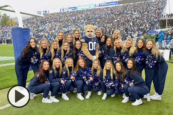 Cosmo Cougar and the BYU Cougarettes pose for a photo next to the football field at LaVell Edwards Stadium.