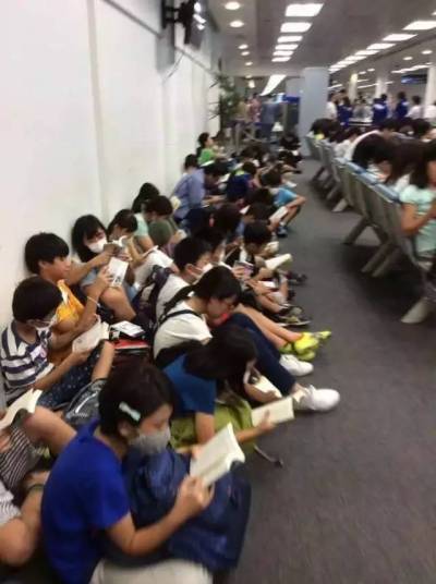 Trong lúc chờ đợi ở sân bay, hàng chục em học sinh Nhật Bản ngay ngắn ngồi trên sàn nhà, tất cả cùng im lặng đọc sách. (Ảnh: Facebook)