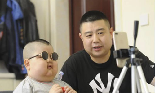 Cậu bé và bố quay video trực tuyến trên mạng xã hội Trung Quốc. Ảnh: The Paper