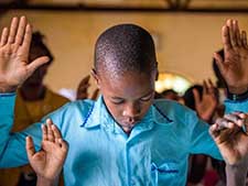 A boy lifts his hand in worship.