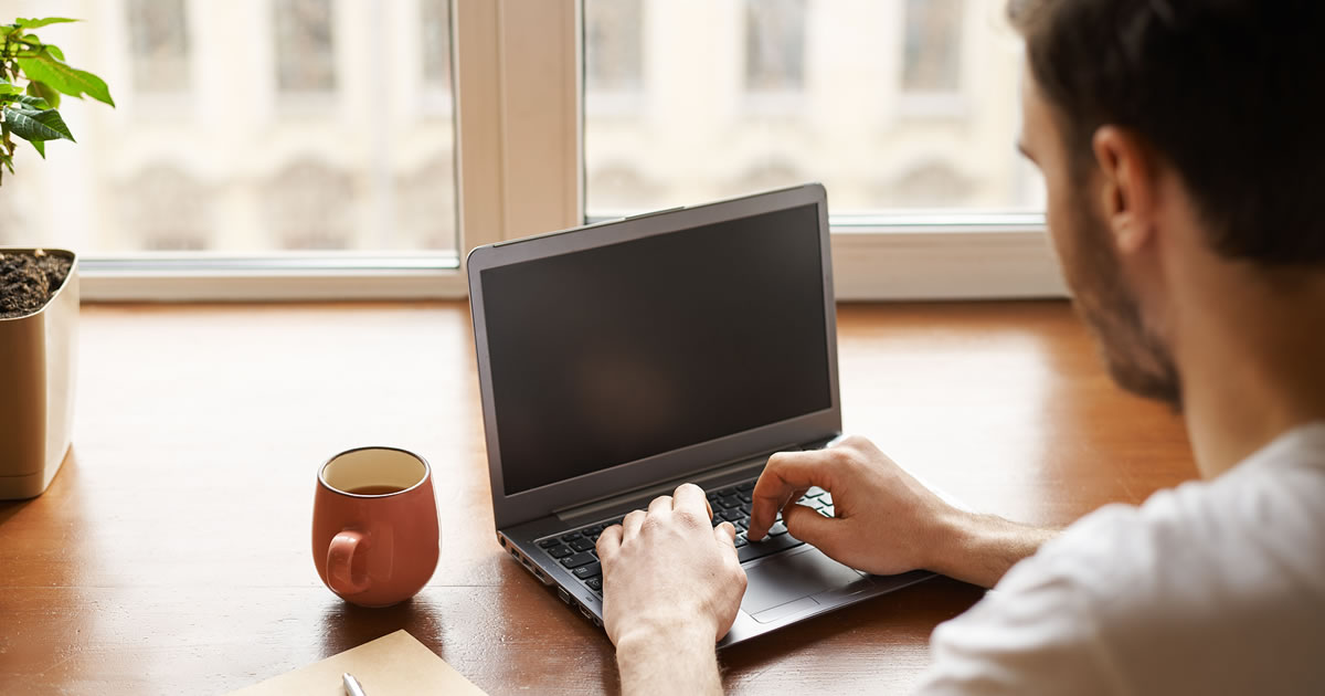 Back view of man at desk typing on laptop