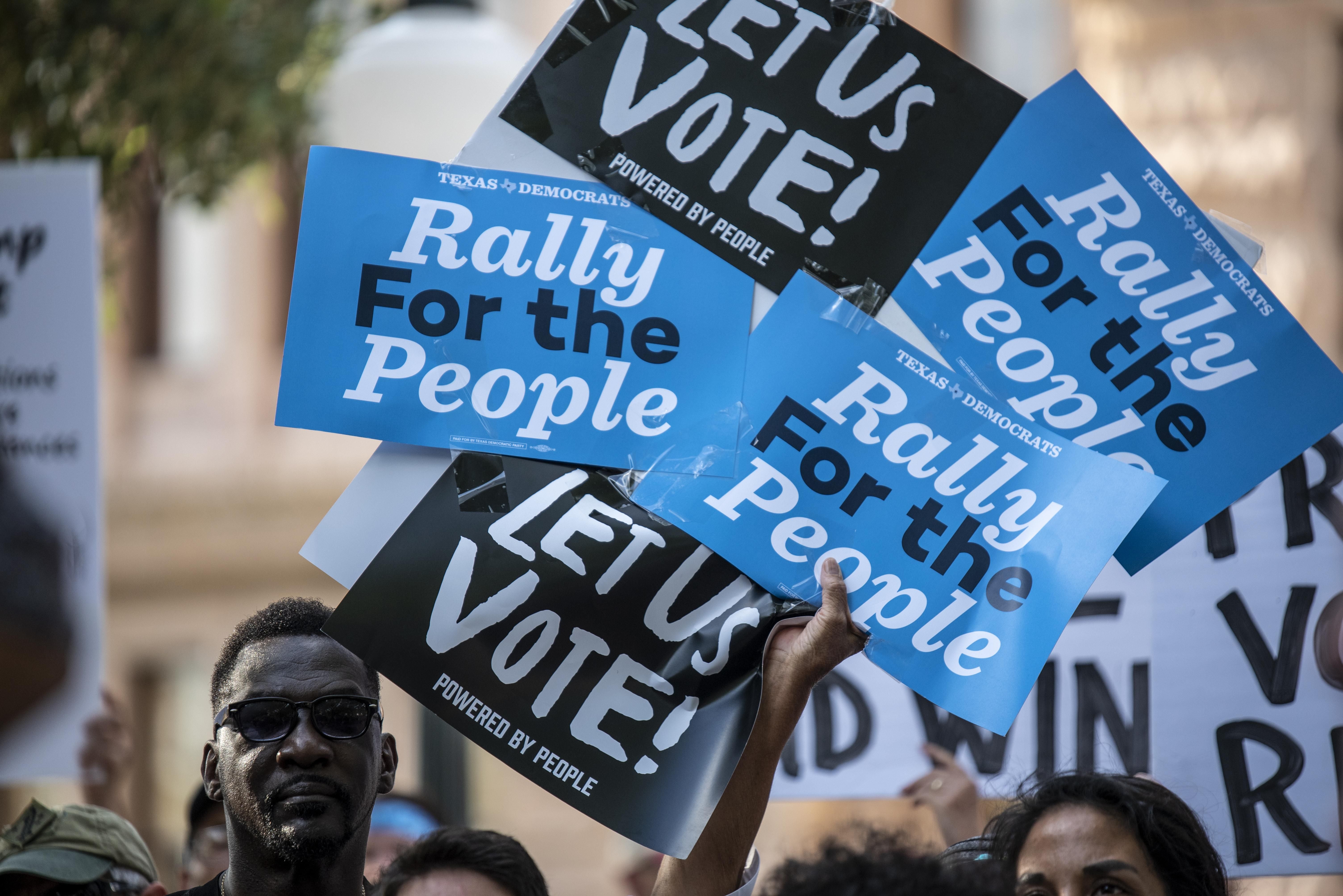Attendees hold up signs during a rally at the state Capitol on June 20, 2021, in Austin, Texas.